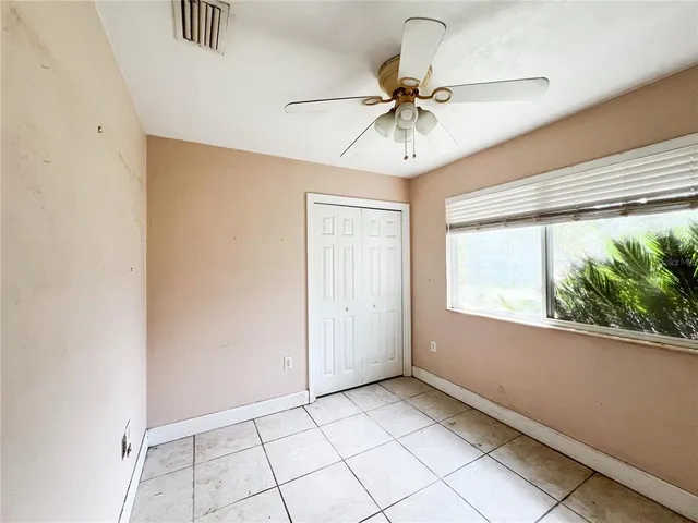 an empty room with windows and fan