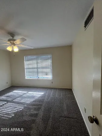 an empty room with windows and fan