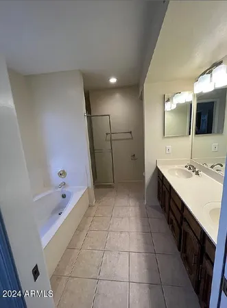 a large bathroom with a double vanity sink a large mirror and a bathtub