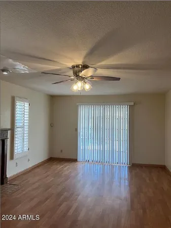 an empty room with wooden floor fan and windows