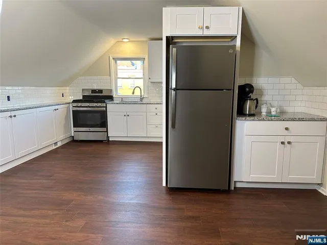 a kitchen with granite countertop white cabinets and stainless steel appliances