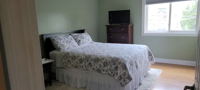 a bedroom with a bed and a flat tv screen on a dresser