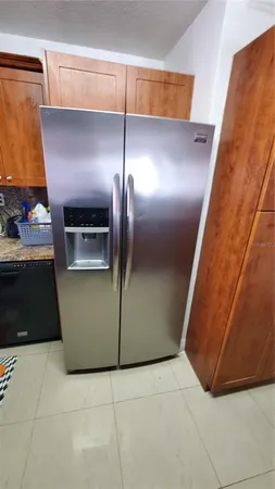 a view of a refrigerator in kitchen and an empty room
