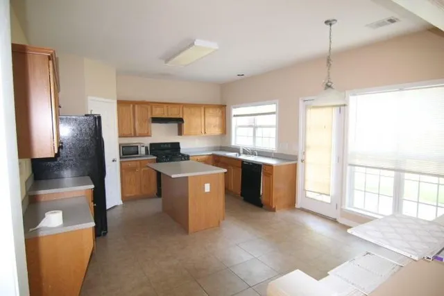 a kitchen with stainless steel appliances granite countertop a refrigerator a sink a stove a microwave a counter space and cabinets