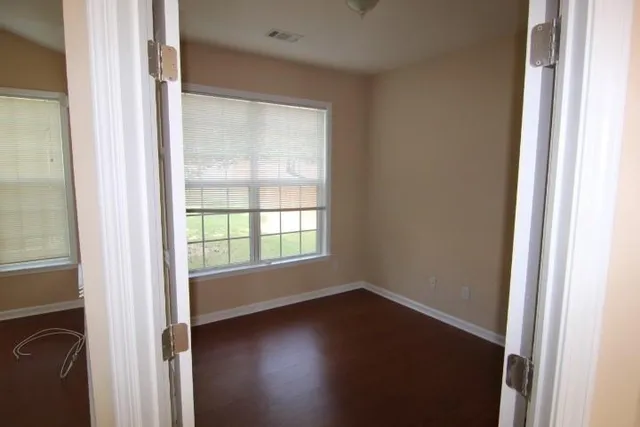 an empty room with wooden floor and windows