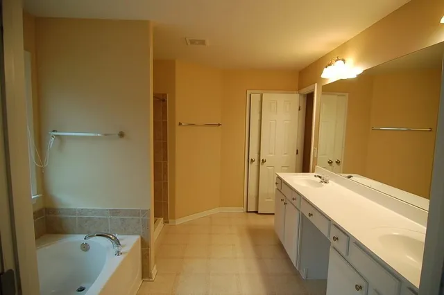 a bathroom with a tub sink vanity granite and shower