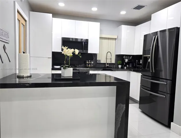 a kitchen with stainless steel appliances granite countertop a refrigerator and a stove