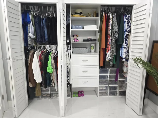a view of walk in closet with clothes and shoes