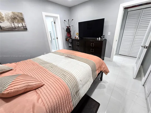 a bedroom with a bed and a flat tv screen on the dresser