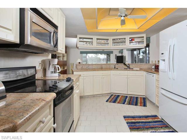 306 Devils Bight Naples, FL 34103 - Photo 5 of 17 a kitchen with stainless steel appliances granite countertop a sink and cabinets