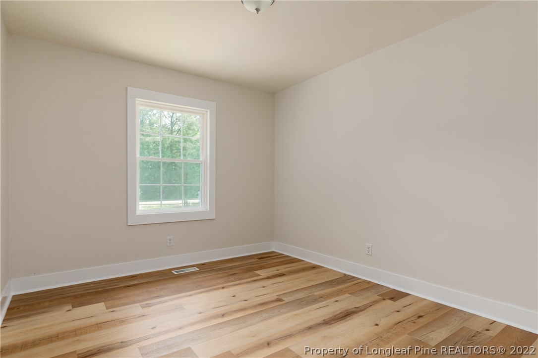 344 J Burns Road Vass, NC 28394 - Photo 17 of 50 an empty room with wooden floor and windows
