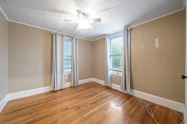 a view of empty room with wooden floor and fan