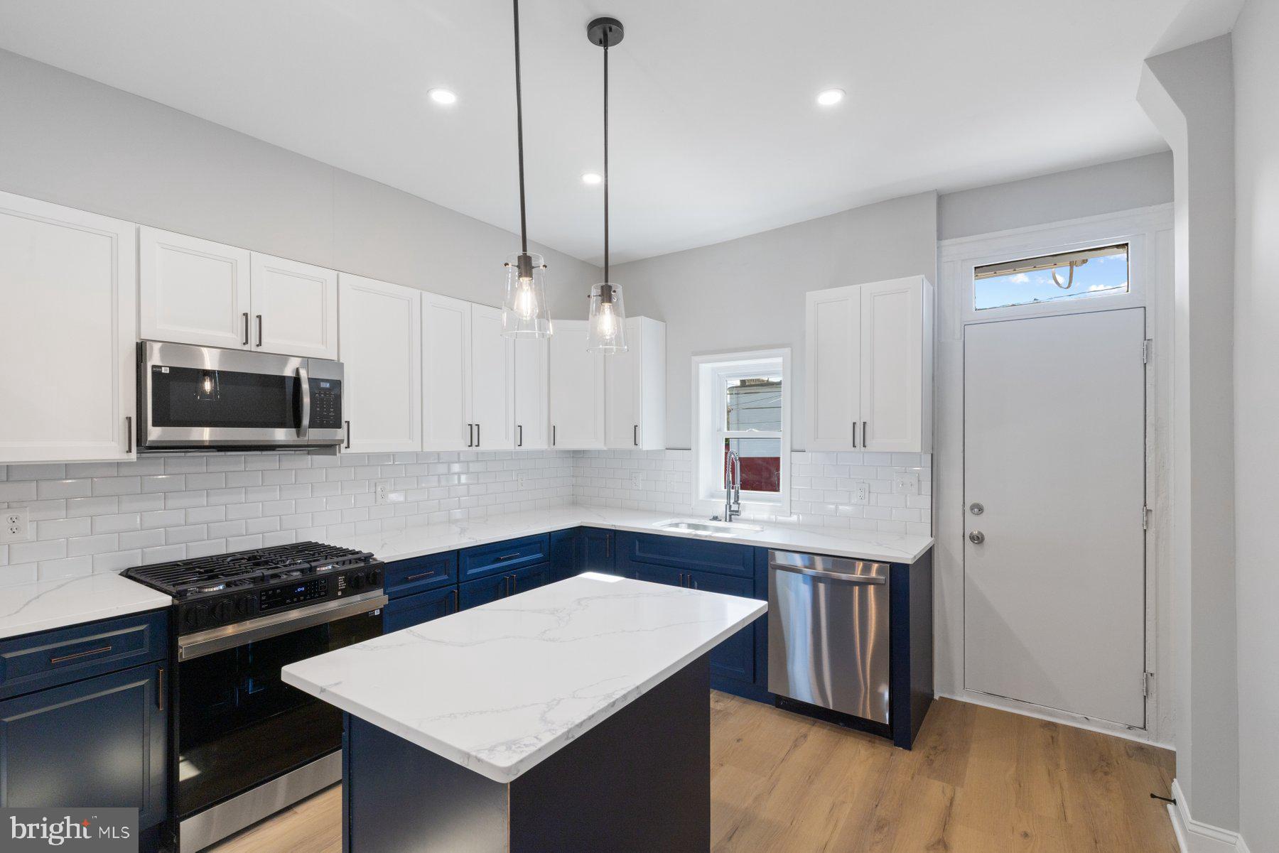653 Bartlett Avenue Baltimore, MD 21218 - Photo 12 of 39 a kitchen with stainless steel appliances a sink a stove a refrigerator and white cabinets with wooden floor