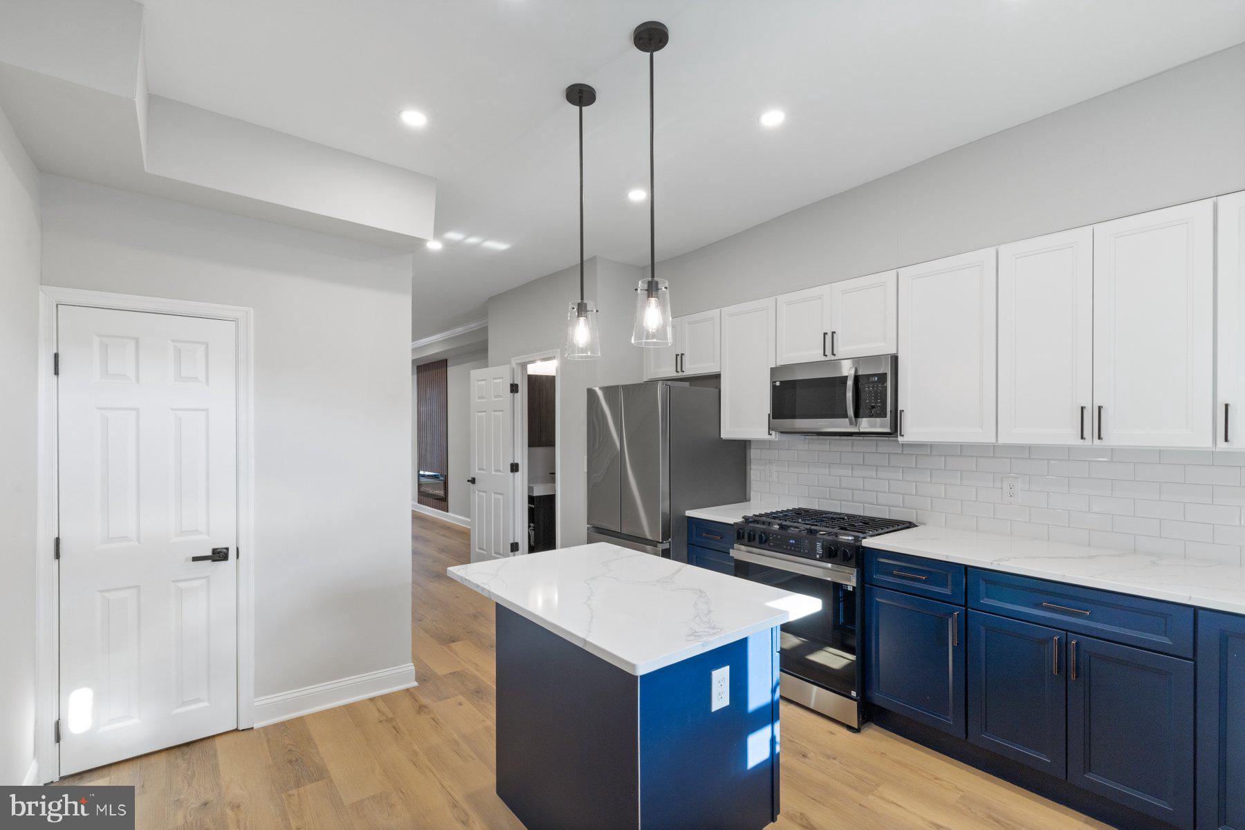 653 Bartlett Avenue Baltimore, MD 21218 - Photo 13 of 39 a kitchen with stainless steel appliances kitchen island granite countertop a refrigerator a sink dishwasher a stove and white cabinets with wooden floor