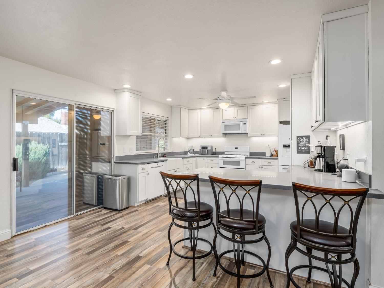 468 Burgan Avenue Clovis, CA 93611 - Photo 10 of 24 a kitchen with a dining table chairs wooden floor cabinets and stainless steel appliances