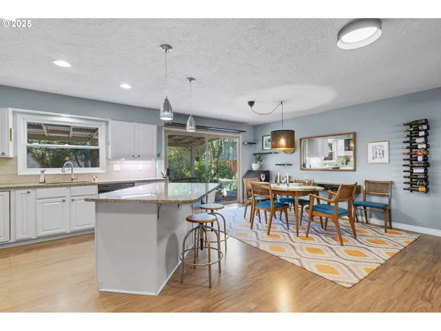 a living room with stainless steel appliances kitchen island granite countertop furniture and a wooden floor