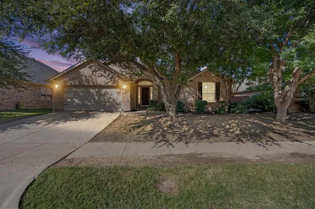 a front view of a house with a yard and large trees