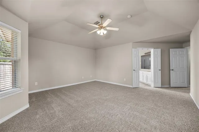 an empty room with chandelier fan and windows