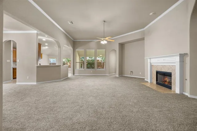 an empty room with a fireplace and chandelier fan