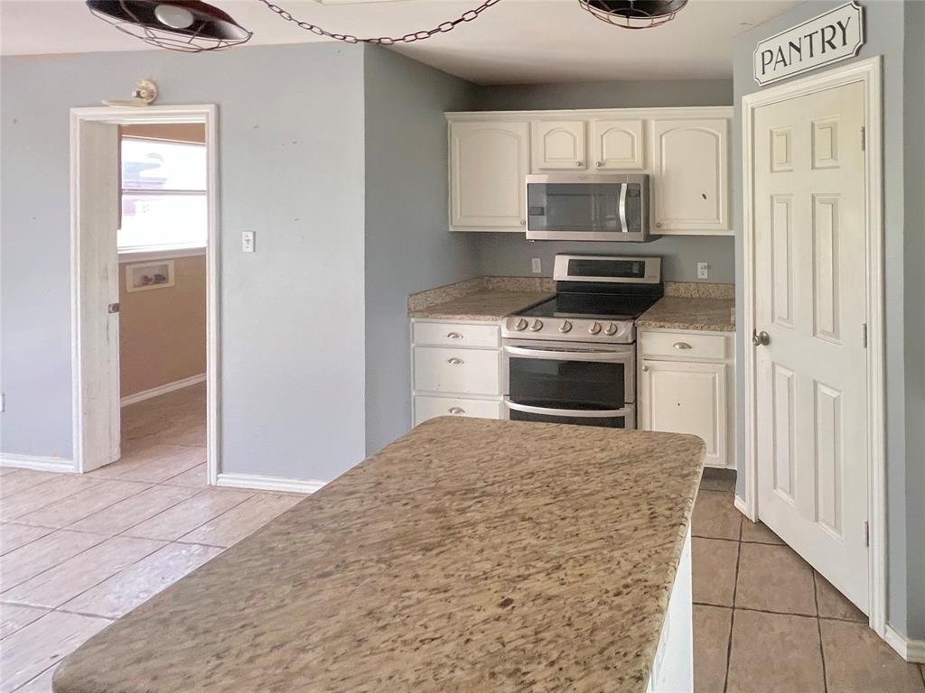 3661 Emo Street Midlothian, TX 76065 - Photo 7 of 24 a kitchen with a stove a microwave and a refrigerator