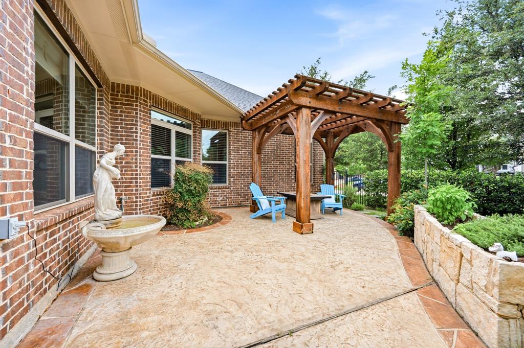 7013 Handel Colleyville, TX 76034 - Photo 30 of 37 Expansive stamped concrete patio featuring a wood pergola and a stone retaining wall