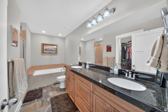 7872 Farm House Lane Midvale, UT 84047 - Photo 19 of 39 Bathroom with dual sink vanity featuring a dark stone countertop and wood-finish cabinetry