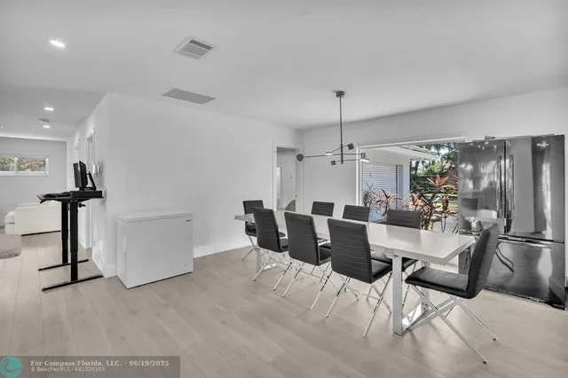a large kitchen with a table chairs stainless steel appliances and cabinets