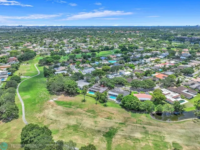 an aerial view of residential houses with outdoor space and trees