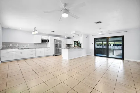 a large white kitchen with a stove a faucet cabinets and a dining table