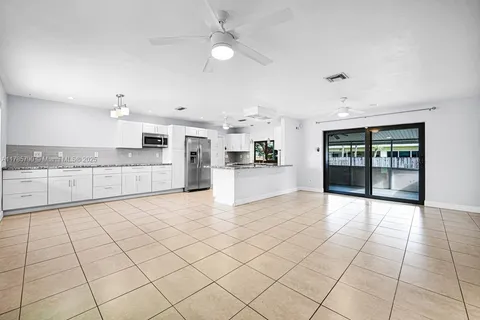 a large white kitchen with a stove a faucet cabinets and a dining table