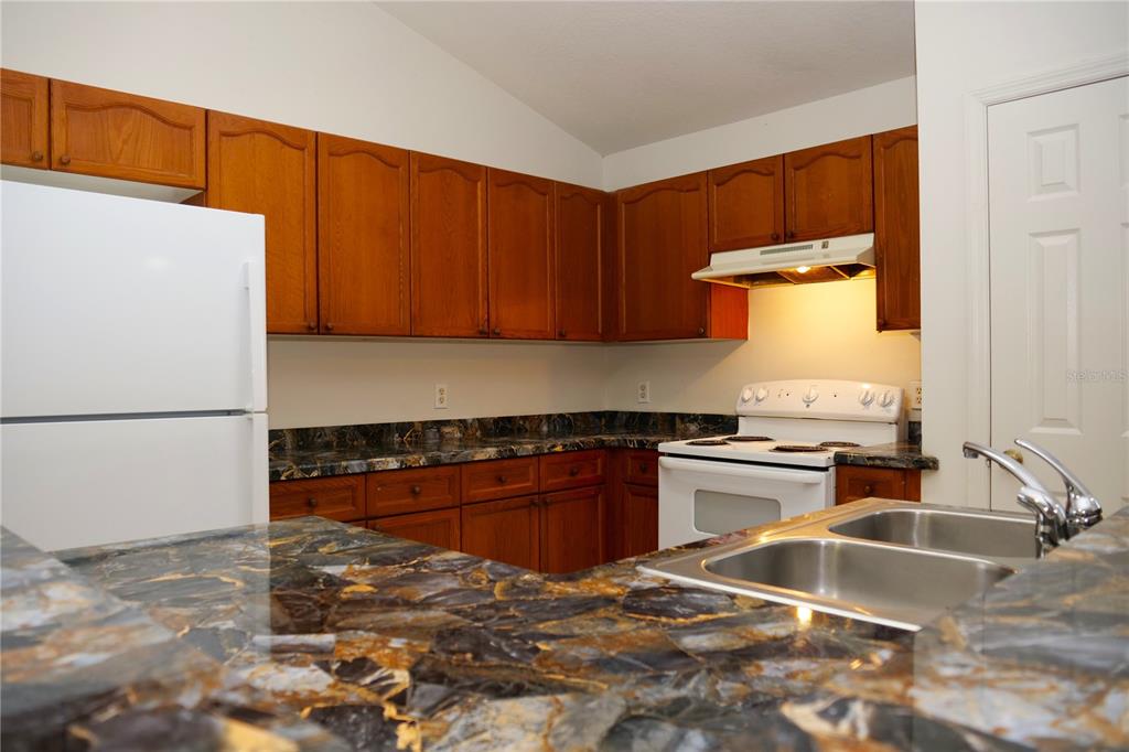 415 Danube Way Kissimmee, FL 34759 - Photo 13 of 17 a kitchen with granite countertop a sink stove and refrigerator