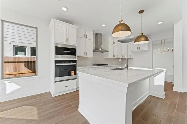 a kitchen with kitchen island granite countertop a sink a stove and a wooden floors