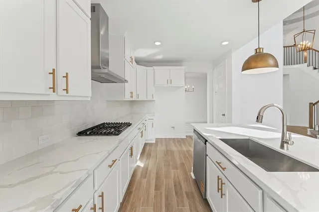 a kitchen with stainless steel appliances granite countertop a sink a stove and a wooden floors