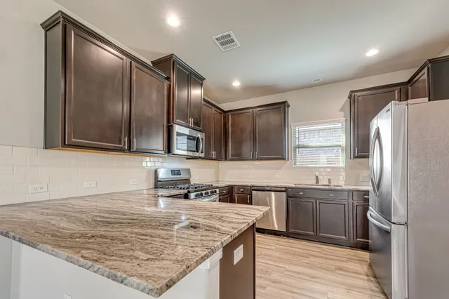 a kitchen with stainless steel appliances granite countertop a sink stove and refrigerator