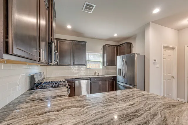 a large kitchen with stainless steel appliances granite countertop a refrigerator and a sink