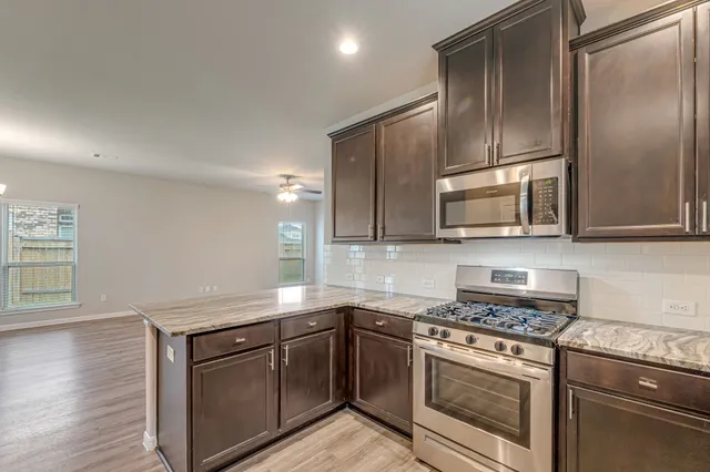 a kitchen with cabinets stainless steel appliances and wooden floor