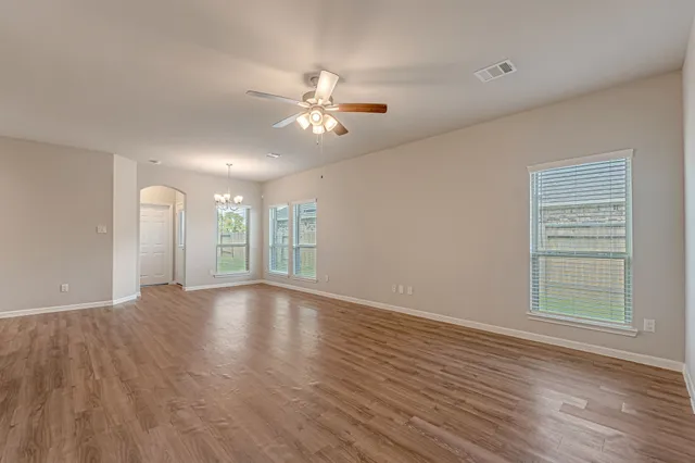 a view of an empty room with a window and wooden floor