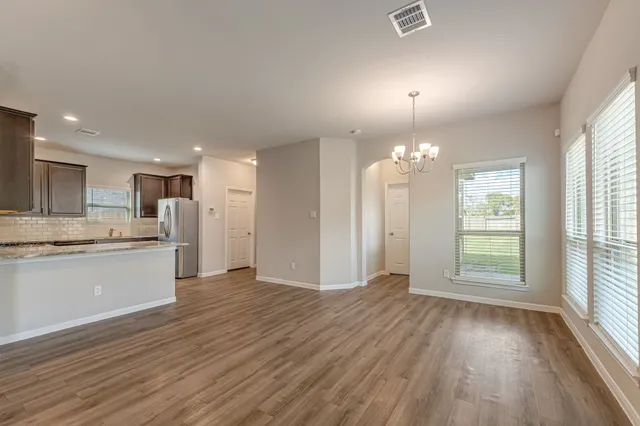 a view of an empty room with window and wooden floor
