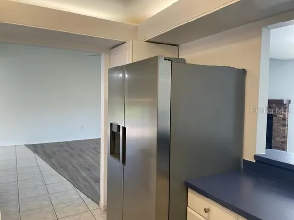 a view of a refrigerator in kitchen and an empty room