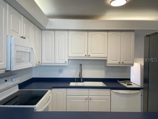 a kitchen with stainless steel appliances granite countertop a sink a stove and white cabinets