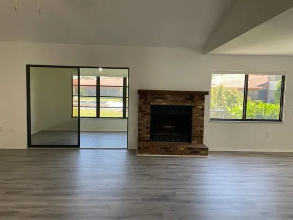 an empty room with wooden floor fireplace and windows