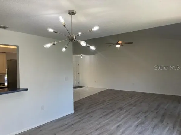 a view of an empty room with wooden floor and a ceiling fan