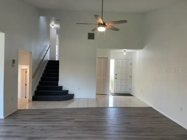 wooden floor in an empty room with a chandelier fan