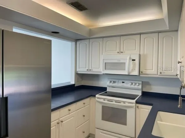 a kitchen with white cabinets and white appliances