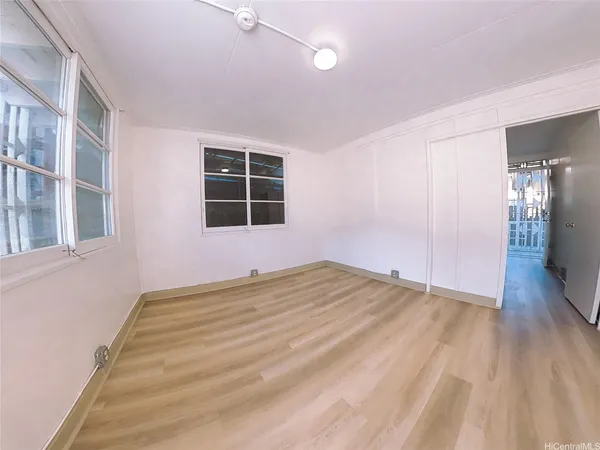 a view of empty room with wooden floor and windows