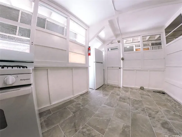 a view of a refrigerator in kitchen and an empty room