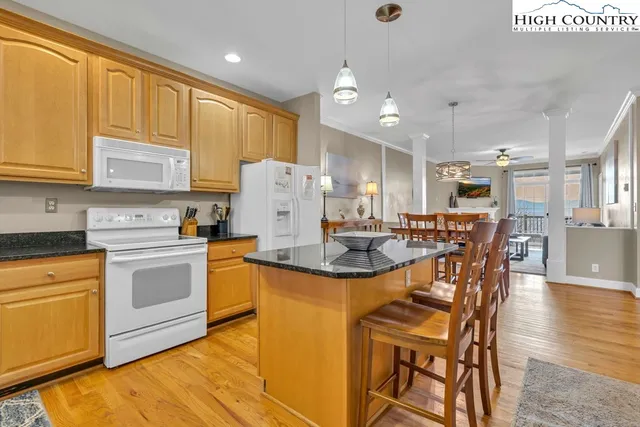a kitchen with stainless steel appliances granite countertop a sink a stove a dining table and chairs