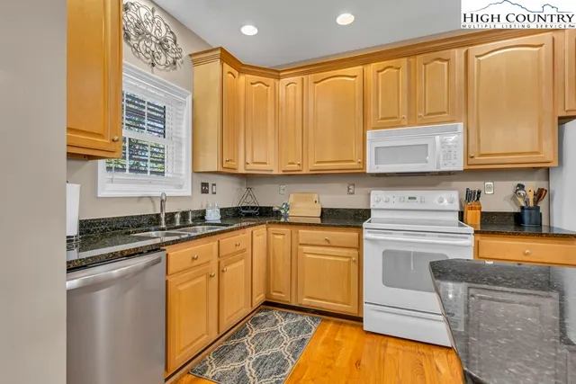 a kitchen with stainless steel appliances granite countertop a table chairs sink and cabinets