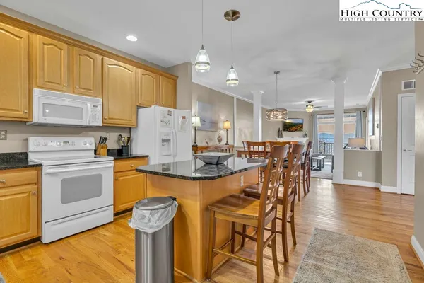 a kitchen with stainless steel appliances kitchen island granite countertop a stove top oven a sink with island and chairs