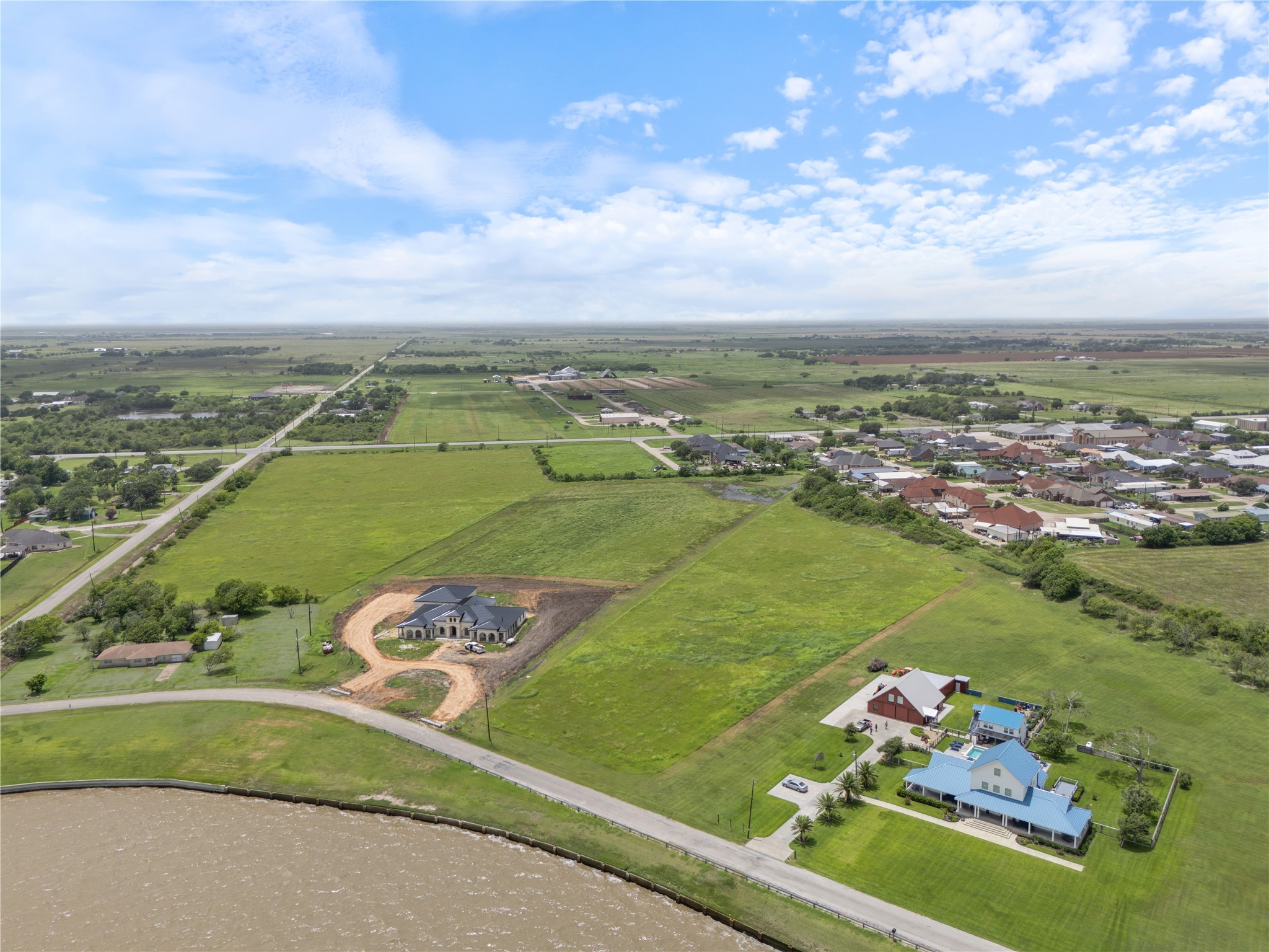 305 Bayshore Road Palacios, TX 77465 - Photo 9 of 25 An aerial perspective showcases a tranquil waterside home alongside verdant, open fields.